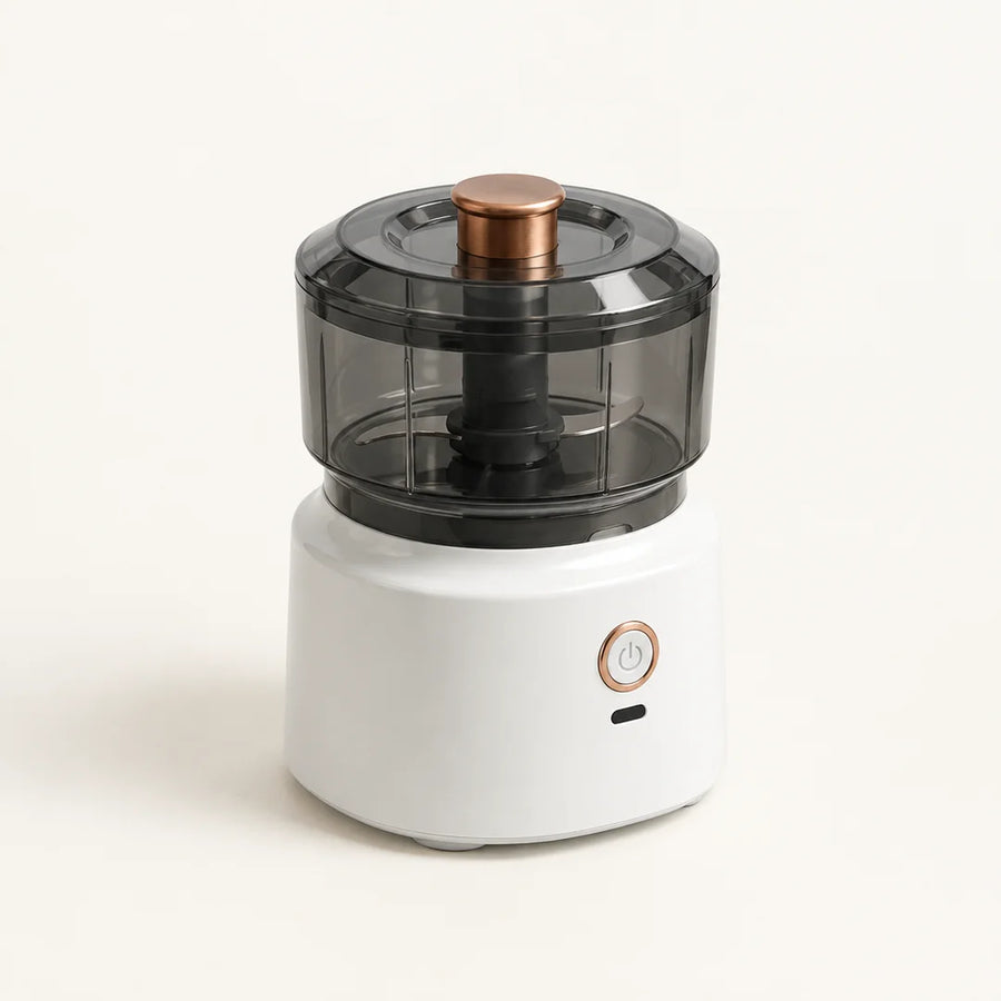 Hachoir électrique sans fil 350 ml à socle blanc, bol et couvercle gris fumé, poussoir cuivré, sur fond blanc cassé