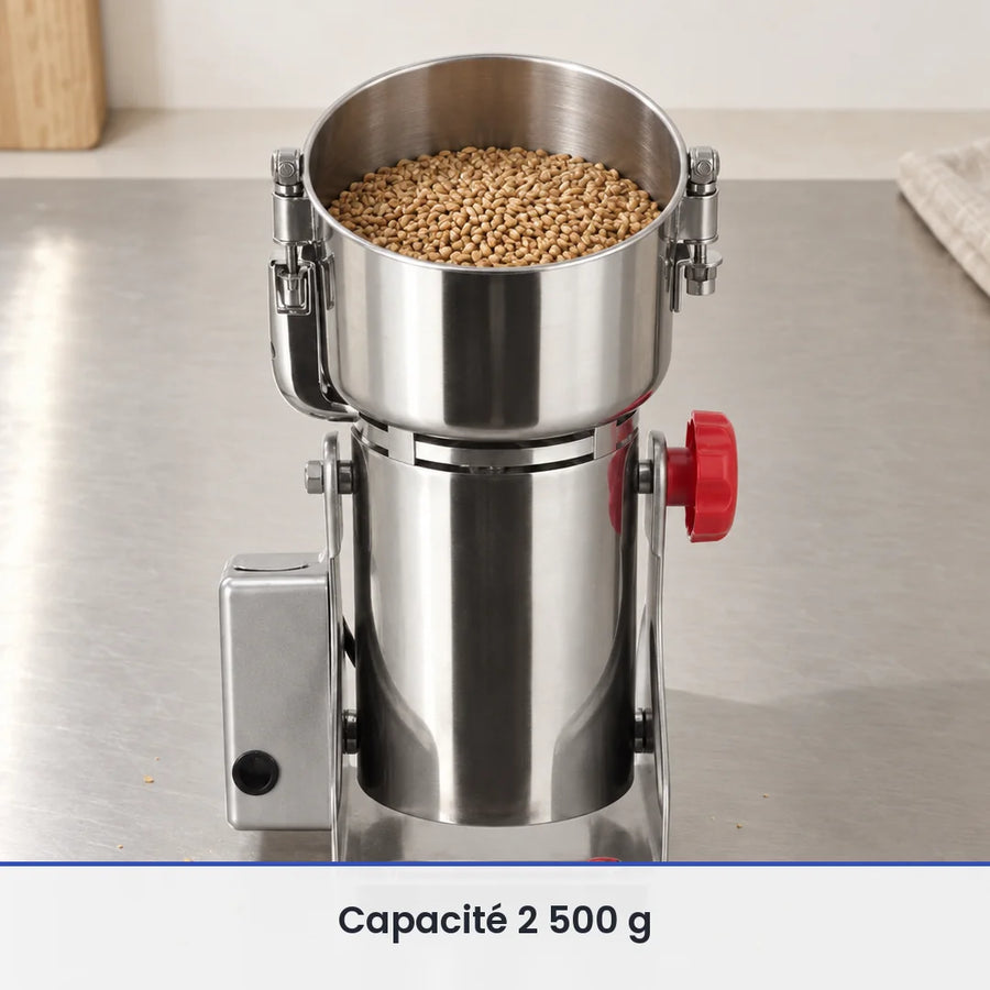 Cuve inox ouverte du grand moulin oscillant 2 500 g remplie aux deux tiers de grains, sur un plan de travail inox brossé