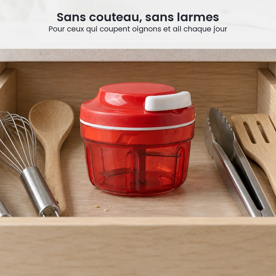 Hachoir manuel à ficelle compact rouge rangé dans un tiroir de cuisine, entre un fouet, une spatule et une pince