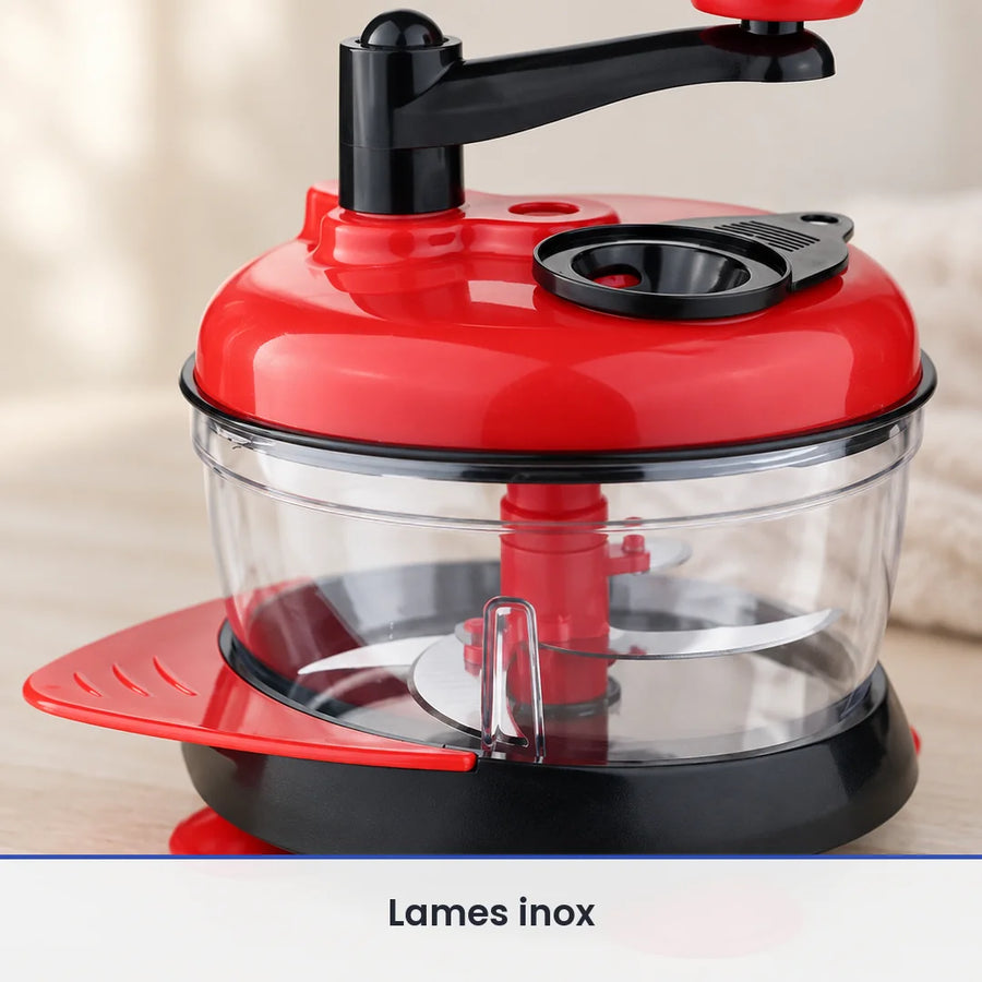Gros plan sur les lames inox au fond du bol transparent du hachoir manuel rouge à manivelle, bol fermé par son couvercle
