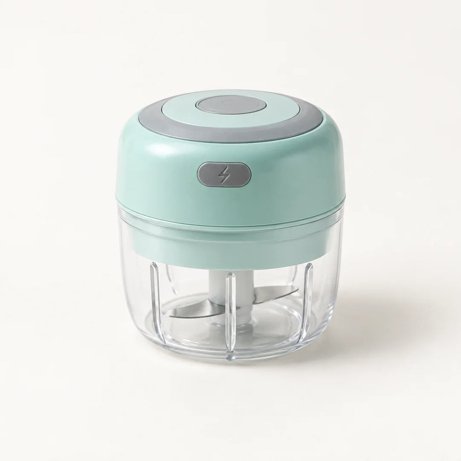 Mini hachoir électrique vert menthe 30 W avec bol transparent de 100 ml et bouton gris à éclair, sur fond blanc cassé