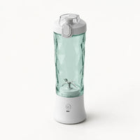 Blender portable 600 ml blanc avec gobelet vert d'eau à facettes et couvercle gris clair à clapet, sur fond blanc cassé
