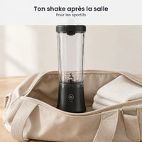 Blender portable noir 600 ml rangé debout dans un sac de sport ouvert, à côté d'une serviette blanche pliée