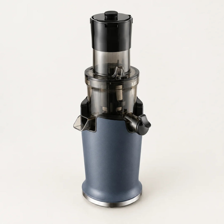 Extracteur de jus vertical bleu ardoise à bol fumé, deux becs noirs et cheminée étroite, vu en plongée sur fond blanc cassé
