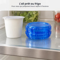Hachoir à ail bleu à torsion fermé sur une étagère de réfrigérateur, à côté d'un pot de yaourt et d'une boîte de salade