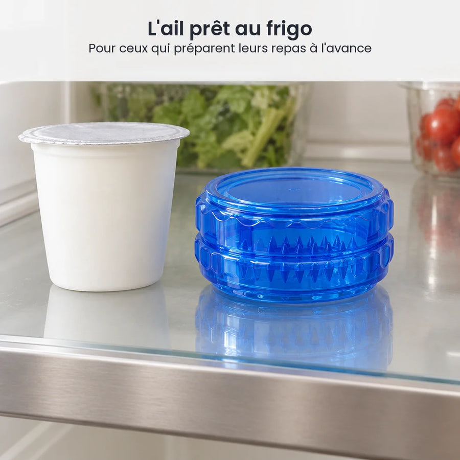 Hachoir à ail bleu à torsion fermé sur une étagère de réfrigérateur, à côté d'un pot de yaourt et d'une boîte de salade