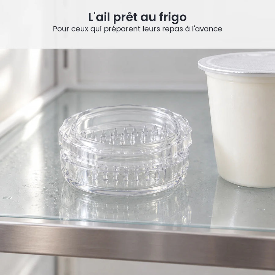 Hachoir à ail transparent fermé, rangé sur une étagère en verre de réfrigérateur à côté d'un pot de yaourt