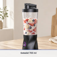 Grand gobelet du blender portable 700 ml rempli aux deux tiers de fraises, banane, myrtilles et lait, sur bois clair