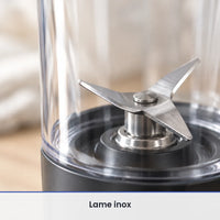 Gros plan sur la lame inox en croix du blender portable 700 ml, vue à travers la paroi du gobelet transparent