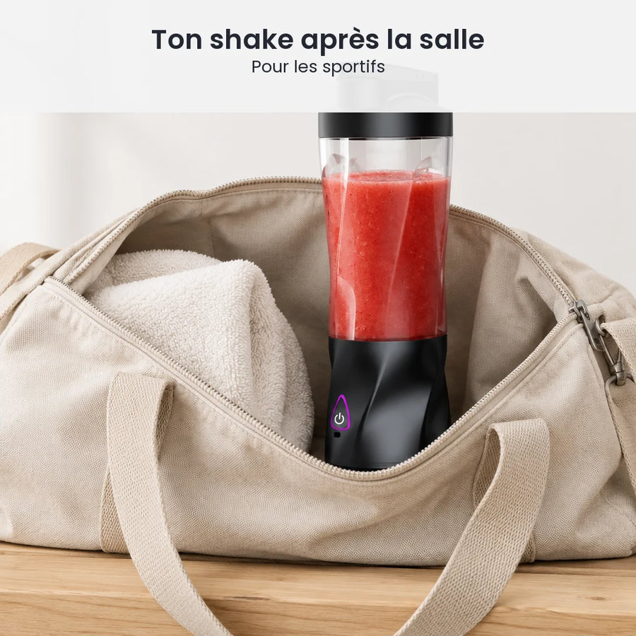 Blender portable 700 ml rempli de smoothie rouge, rangé debout dans un sac de sport ouvert à côté d'une serviette