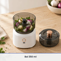 Bol gris fumé de 350 ml rempli d'oignon rouge, d'ail et d'herbes sur le socle blanc, couvercle à poussoir cuivré à côté