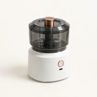 Hachoir électrique sans fil 350 ml à socle blanc, bol et couvercle gris fumé, poussoir cuivré, sur fond blanc cassé