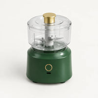 Hachoir électrique sans fil 350 ml à socle vert sapin, bol et couvercle transparents, poussoir doré, sur fond blanc cassé
