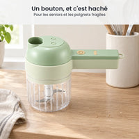Hachoir électrique 4 en 1 sans fil vert pâle rangé sur un plan de travail clair, à côté d'un pot d'ustensiles en bois