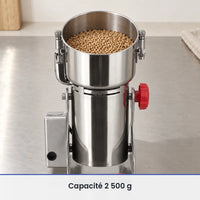 Cuve inox ouverte du grand moulin oscillant 2 500 g remplie aux deux tiers de grains, sur un plan de travail inox brossé
