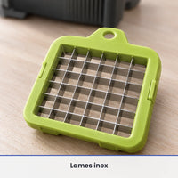 Gros plan sur une grille de découpe verte du coupe-légumes 14 en 1 et ses lames inox croisées, posée sur du bois clair
