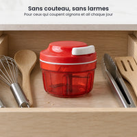 Hachoir manuel à ficelle compact rouge rangé dans un tiroir de cuisine, entre un fouet, une spatule et une pince