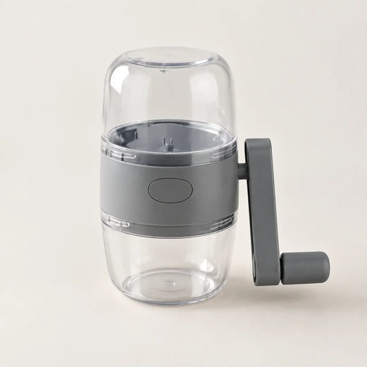 Hachoir à noix manuel gris : réservoir transparent sur le dessus, manivelle grise à droite, petit bac transparent