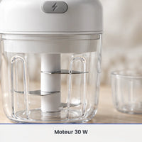 Gros plan sur le couteau inox du mini hachoir électrique blanc, vu à travers la paroi du bol transparent de 250 ml fermé