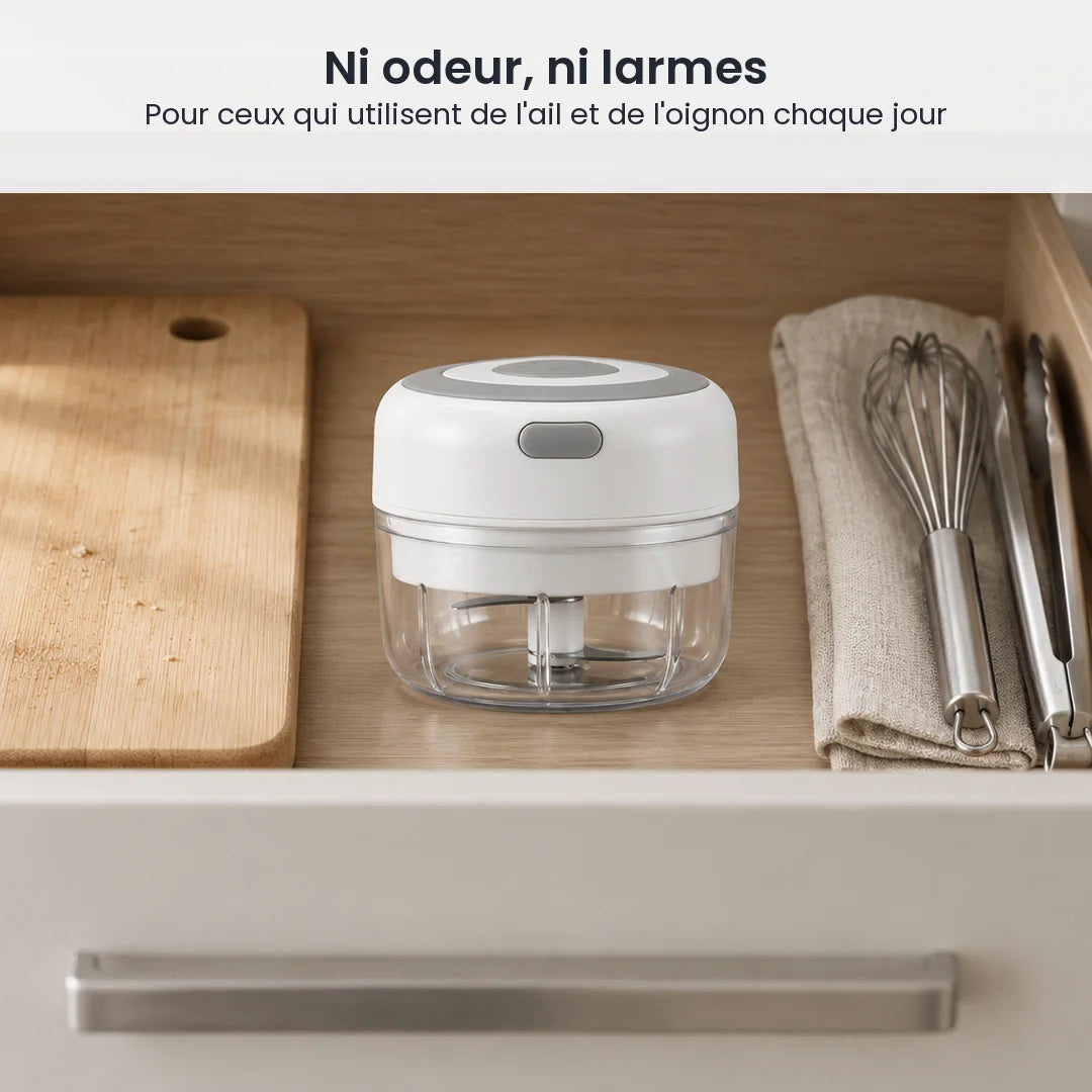 Mini hachoir électrique blanc 100 ml rangé dans un tiroir de cuisine en bois clair, à côté d'ustensiles et d'une planche