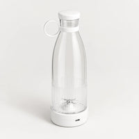 Blender bouteille portable blanc avec bouteille transparente à fond strié, bouchon blanc à anneau, sur fond blanc cassé