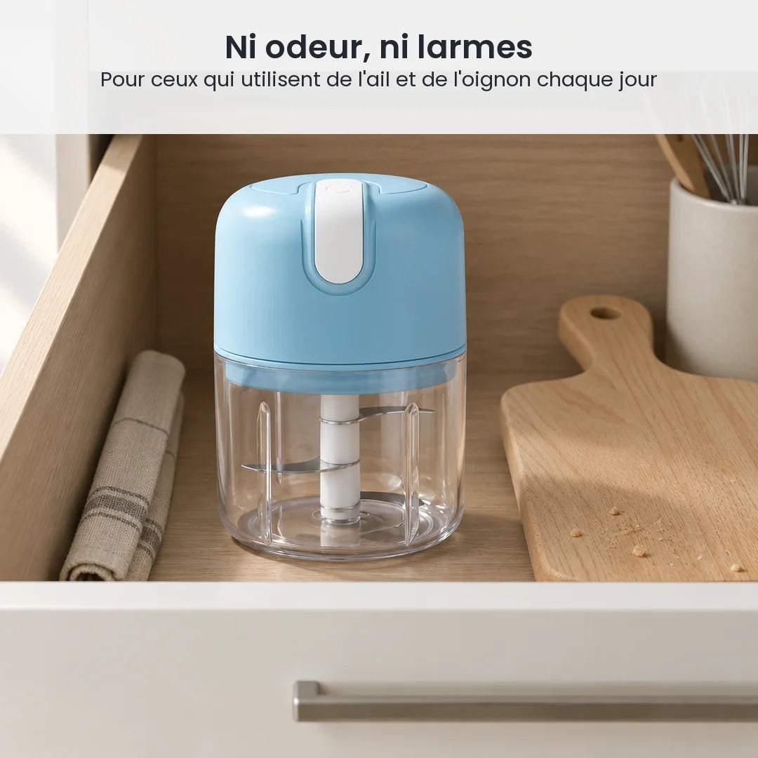 Mini hachoir électrique portable bleu ciel rangé dans un tiroir de cuisine, à côté d'un torchon et d'une planche en bois