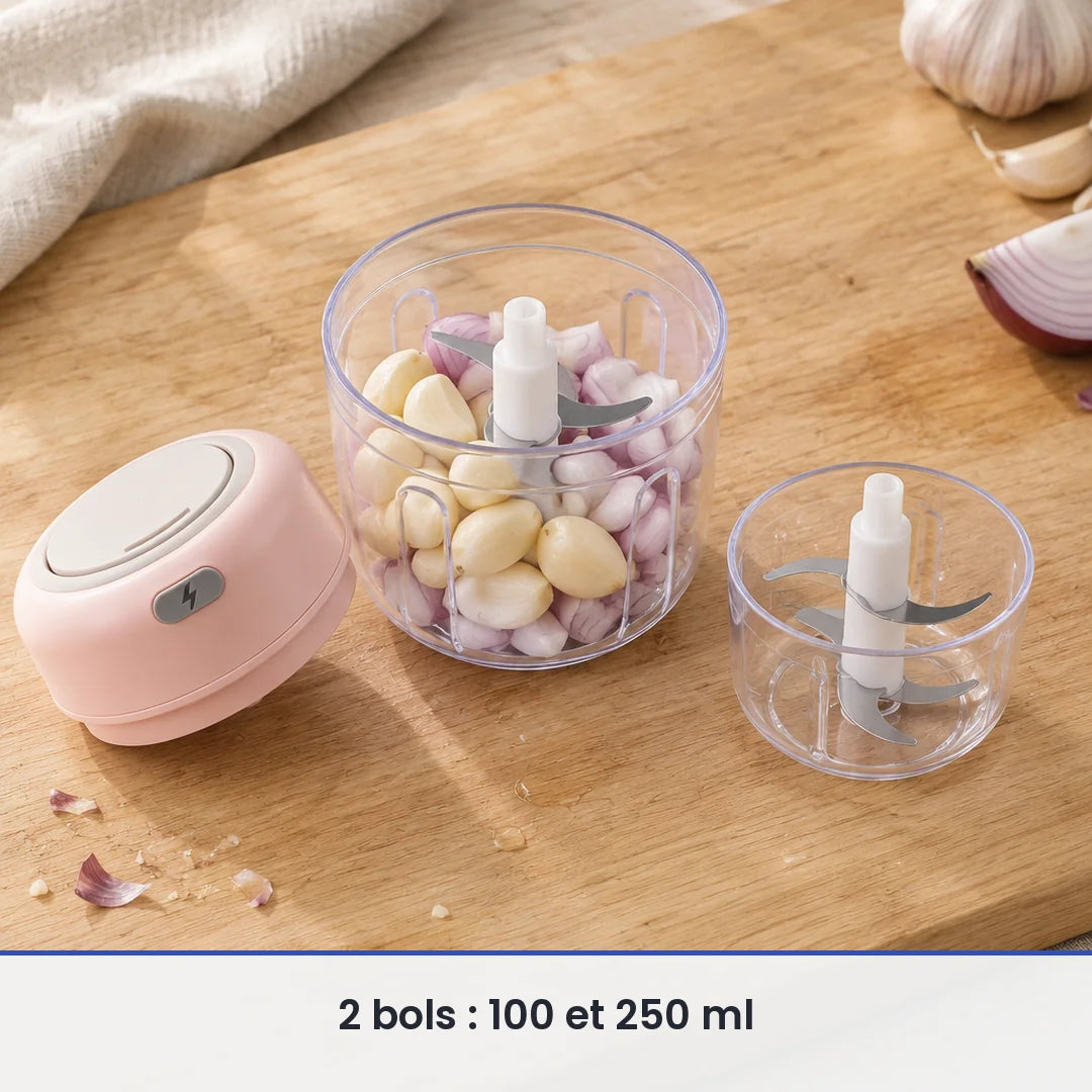 Bol de 250 ml du mini hachoir rose rempli d'ail et d'échalote, couvercle-moteur rose et bol de 100 ml posés à côté