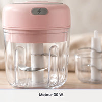 Gros plan sur le couteau inox du mini hachoir électrique rose, vu à travers la paroi du bol transparent de 250 ml fermé