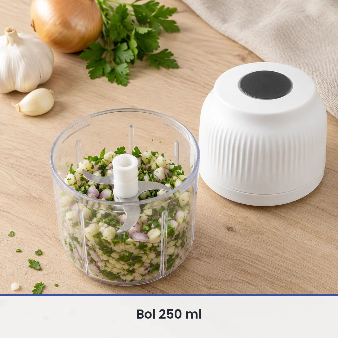 Bol de 250 ml du mini hachoir sans fil blanc rempli d'ail, d'oignon et d'herbes hachés, couvercle-moteur posé à côté