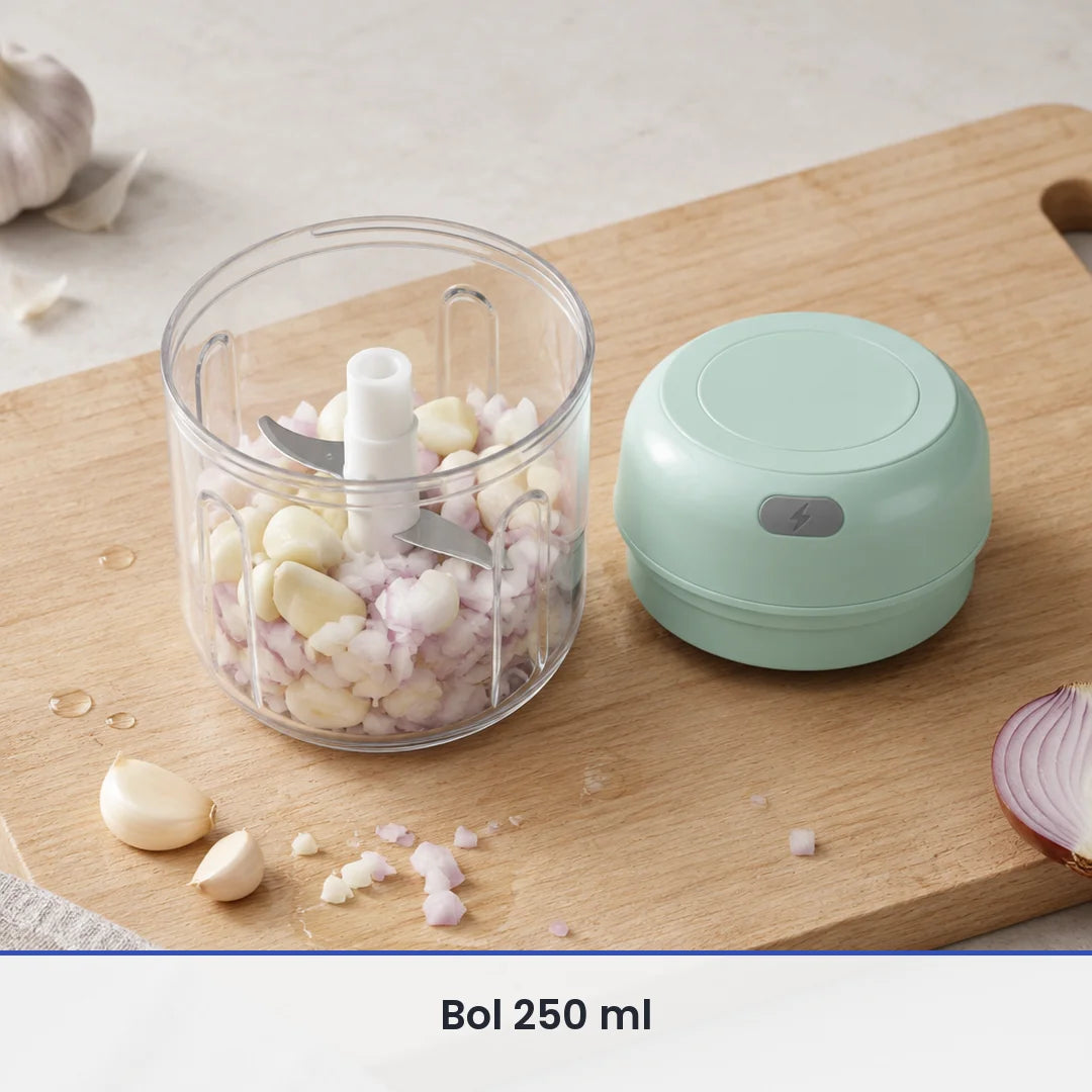 Bol transparent de 250 ml du mini hachoir vert menthe rempli d'ail et d'oignon, couvercle-moteur posé sur la planche